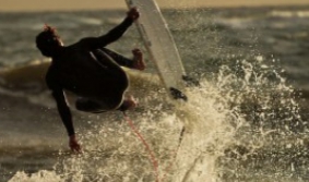 Imágen de una persona surfeando en una playa